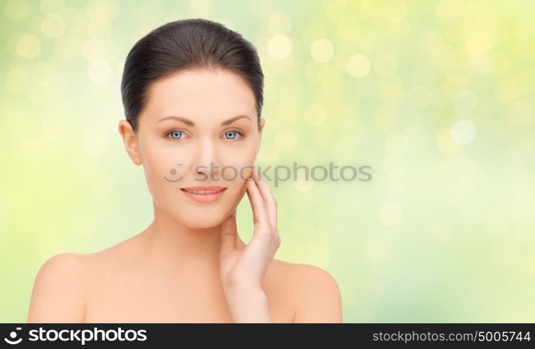 beauty, people and health concept - close up of beautiful young woman face over green lights background. close up of beautiful young woman face