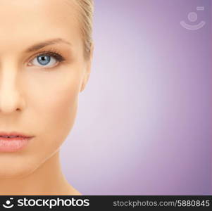 beauty, people and health concept - close up of beautiful young woman half face over violet background