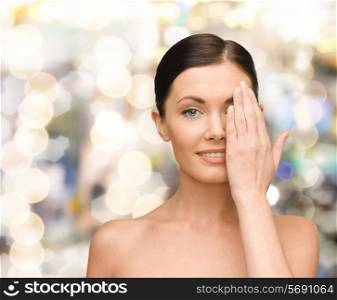 beauty, people and health concept - smiling young woman covering half of face with hand over lights background