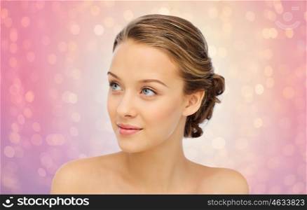 beauty, people and health concept - smiling young woman face and shoulders over rose quartz and serenity lights background