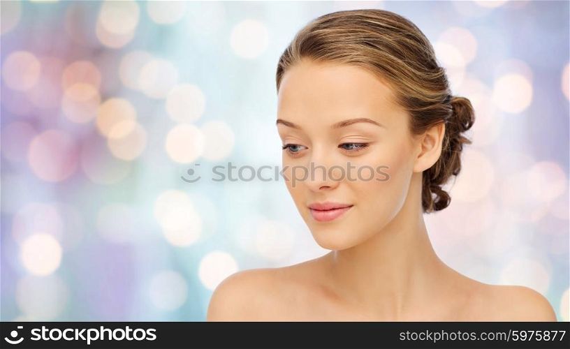 beauty, people and health concept - smiling young woman face and shoulders over purple holidays lights background