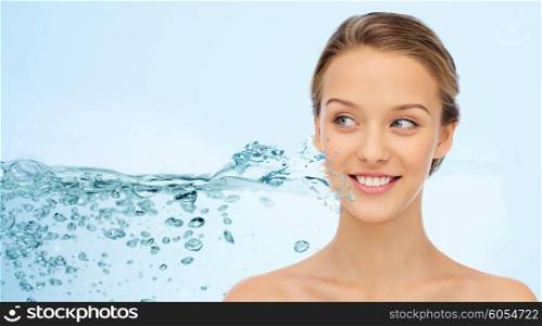 beauty, people and health concept - smiling young woman face and shoulders over water splash and blue background