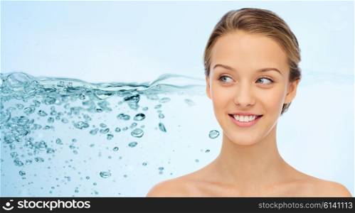 beauty, people and health concept - smiling young woman face and shoulders over water splash on blue background