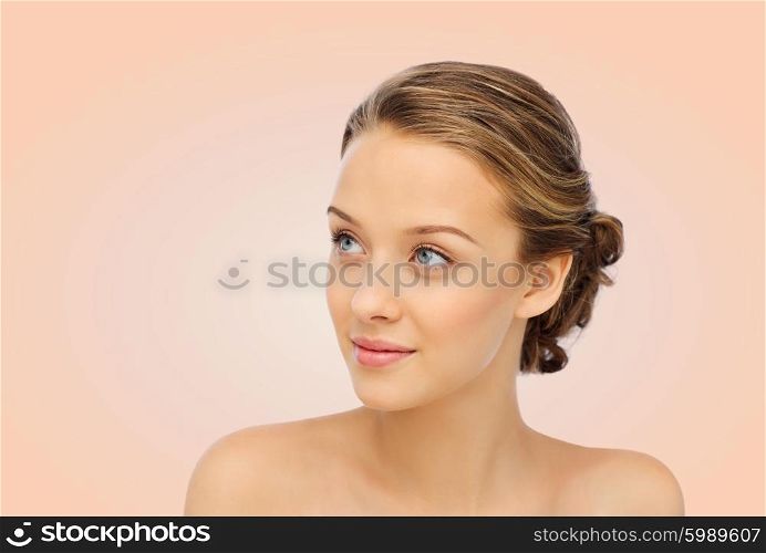 beauty, people and health concept - smiling young woman face and shoulders over beige background
