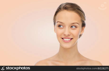 beauty, people and health concept - smiling young woman face and shoulders over beige background