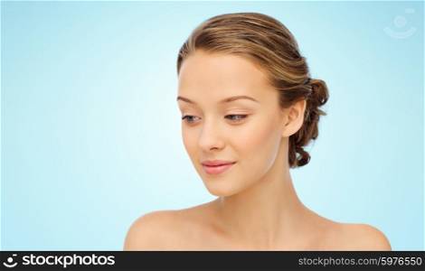 beauty, people and health concept - smiling young woman face and shoulders over blue background