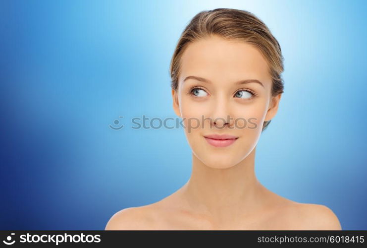 beauty, people and health concept - smiling young woman face and shoulders over blue background