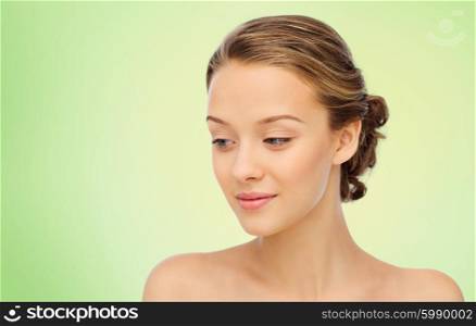 beauty, people and health concept - smiling young woman face and shoulders over green background