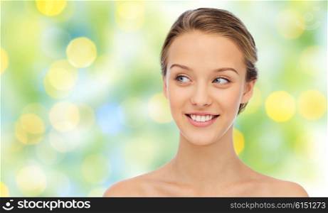 beauty, people and health concept - smiling young woman face and shoulders over green lights background
