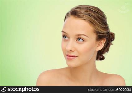 beauty, people and health concept - smiling young woman face and shoulders over green natural background