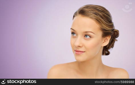 beauty, people and health concept - smiling young woman face and shoulders over violet background