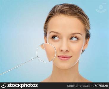 beauty, people and health concept - smiling young woman face over blue background with magnifier showing perfect skin
