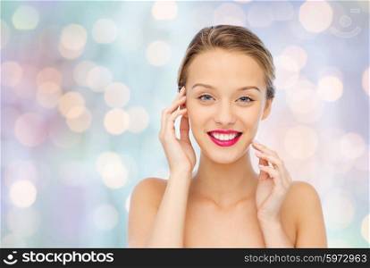 beauty, people and health concept - smiling young woman face with pink lipstick on lips and shoulders over blue holidays lights background