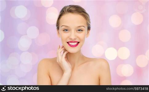 beauty, people and health concept - smiling young woman face with pink lipstick on lips and shoulders over pink lights background