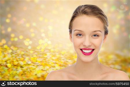 beauty, people and health concept - smiling young woman face with pink lipstick on lips and shoulders over golden glitter or holidays lights background