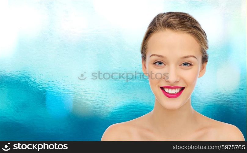 beauty, people and health concept - smiling young woman face with pink lipstick on lips and shoulders