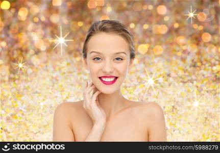 beauty, people and health concept - smiling young woman face with pink lipstick on lips and shoulders over golden glitter background