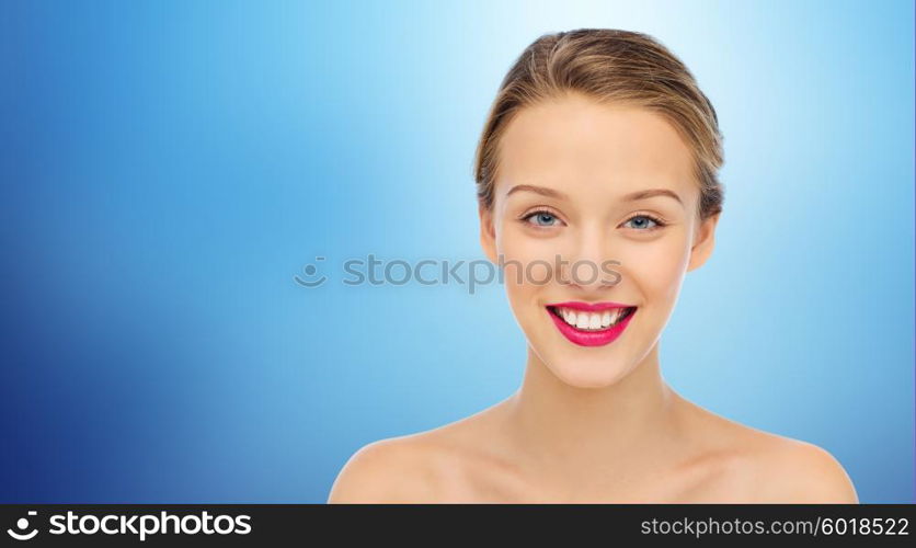 beauty, people and health concept - smiling young woman face with pink lipstick on lips and shoulders over blue background