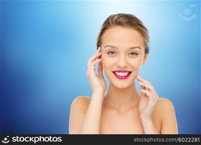 beauty, people and health concept - smiling young woman face with pink lipstick on lips and shoulders over marine blue background