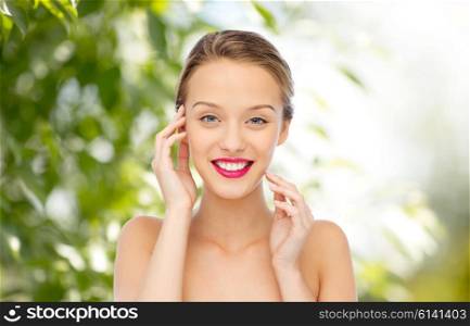beauty, people and health concept - smiling young woman face with pink lipstick on lips and shoulders over green natural background
