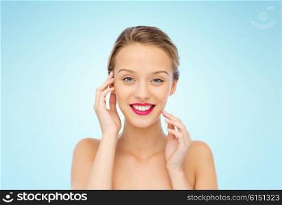 beauty, people and health concept - smiling young woman face with pink lipstick on lips and shoulders over blue background