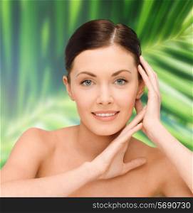 beauty, people and health concept - smiling young woman with bare shoulders over palm tree leaves background