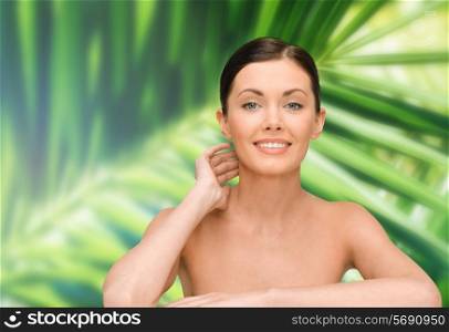 beauty, people and health concept - smiling young woman with bare shoulders over palm tree leaves background