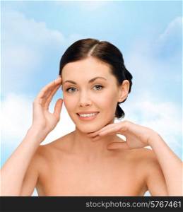 beauty, people and health concept - smiling young woman with bare shoulders over blue sky background