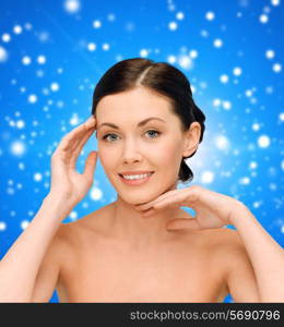 beauty, people and health concept - smiling young woman with bare shoulders over blue snowy background