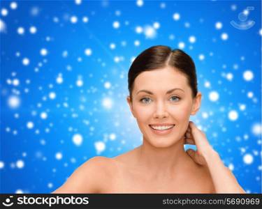 beauty, people and health concept - smiling young woman with bare shoulders over blue snowy background