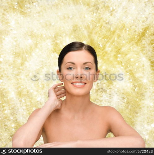 beauty, people and health concept - smiling young woman with bare shoulders over yellow lights background