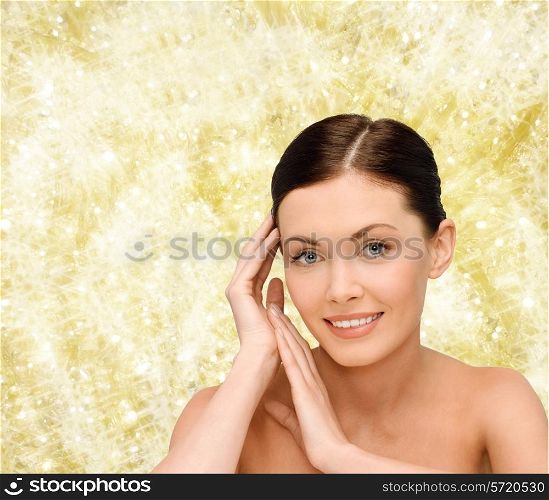 beauty, people and health concept - smiling young woman with bare shoulders over yellow lights background