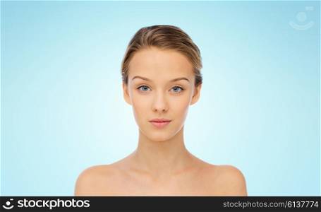 beauty, people and health concept - young woman face and shoulders over blue background