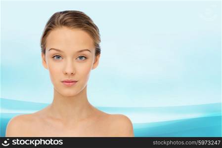 beauty, people and health concept - young woman face and shoulders over blue wavy background