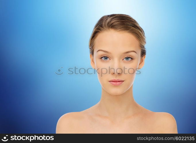 beauty, people and health concept - young woman face and shoulders over marine blue background