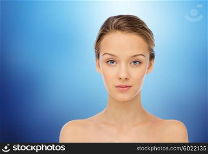 beauty, people and health concept - young woman face and shoulders over marine blue background