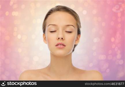 beauty, people and health concept - young woman face with closed eyes and shoulders over rose quartz and serenity lights background
