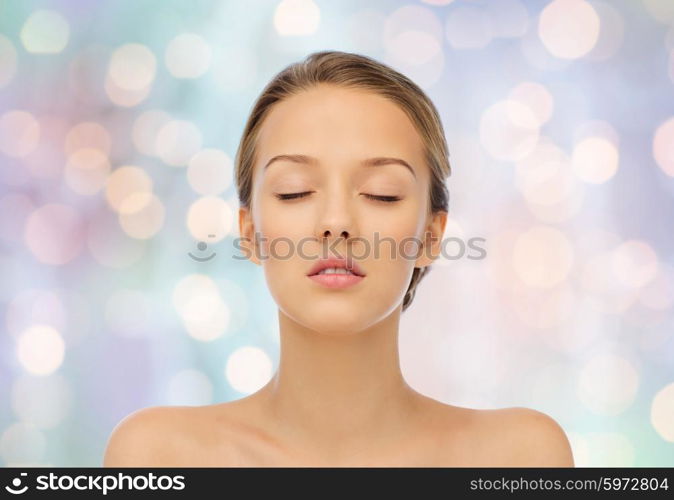 beauty, people and health concept - young woman face with closed eyes and shoulders over blue holidays lights background