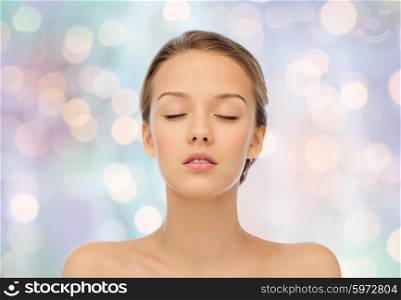 beauty, people and health concept - young woman face with closed eyes and shoulders over blue holidays lights background