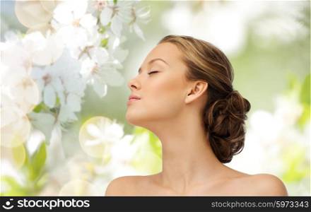 beauty, people and health concept - young woman face with closed eyes and shoulders side view over cherry blossom background