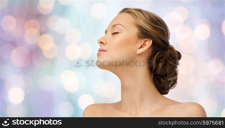 beauty, people and health concept - young woman face with closed eyes and shoulders side view over purple holidays lights background