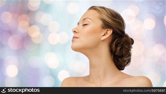 beauty, people and health concept - young woman face with closed eyes and shoulders side view over purple holidays lights background