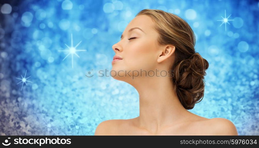 beauty, people and health concept - young woman face with closed eyes and shoulders side view over blue holidays lights or glitter background