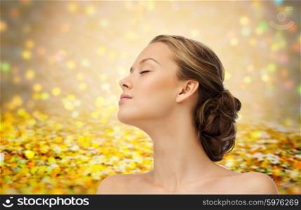 beauty, people and health concept - young woman face with closed eyes and shoulders side view over golden holidays lights or yellow glitter background