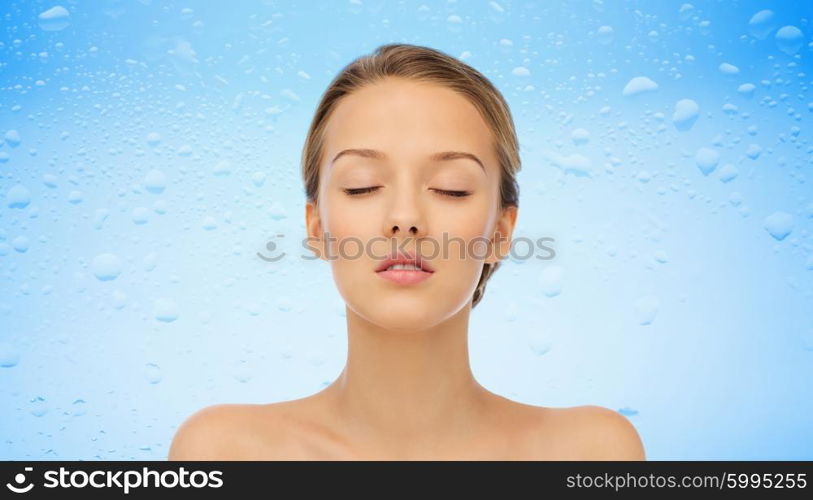 beauty, people and health concept - young woman face with closed eyes and shoulders over water drops on blue background