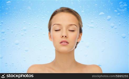 beauty, people and health concept - young woman face with closed eyes and shoulders over water drops on blue background