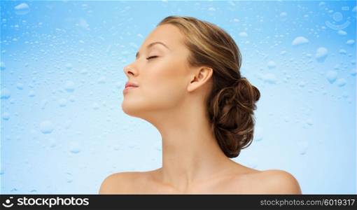 beauty, people and health concept - young woman face with closed eyes and shoulders side view over water drops on blue background