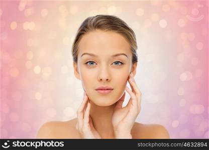 beauty, people and health concept - young woman with bare shoulders touching her face over rose quartz and serenity lights background