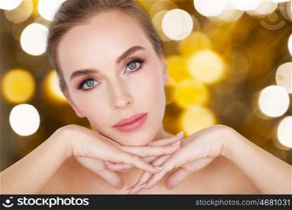 beauty, people and holidays concept - beautiful young woman face and hands over lights background