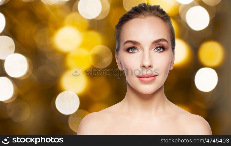 beauty, people and holidays concept - beautiful young woman face over lights background